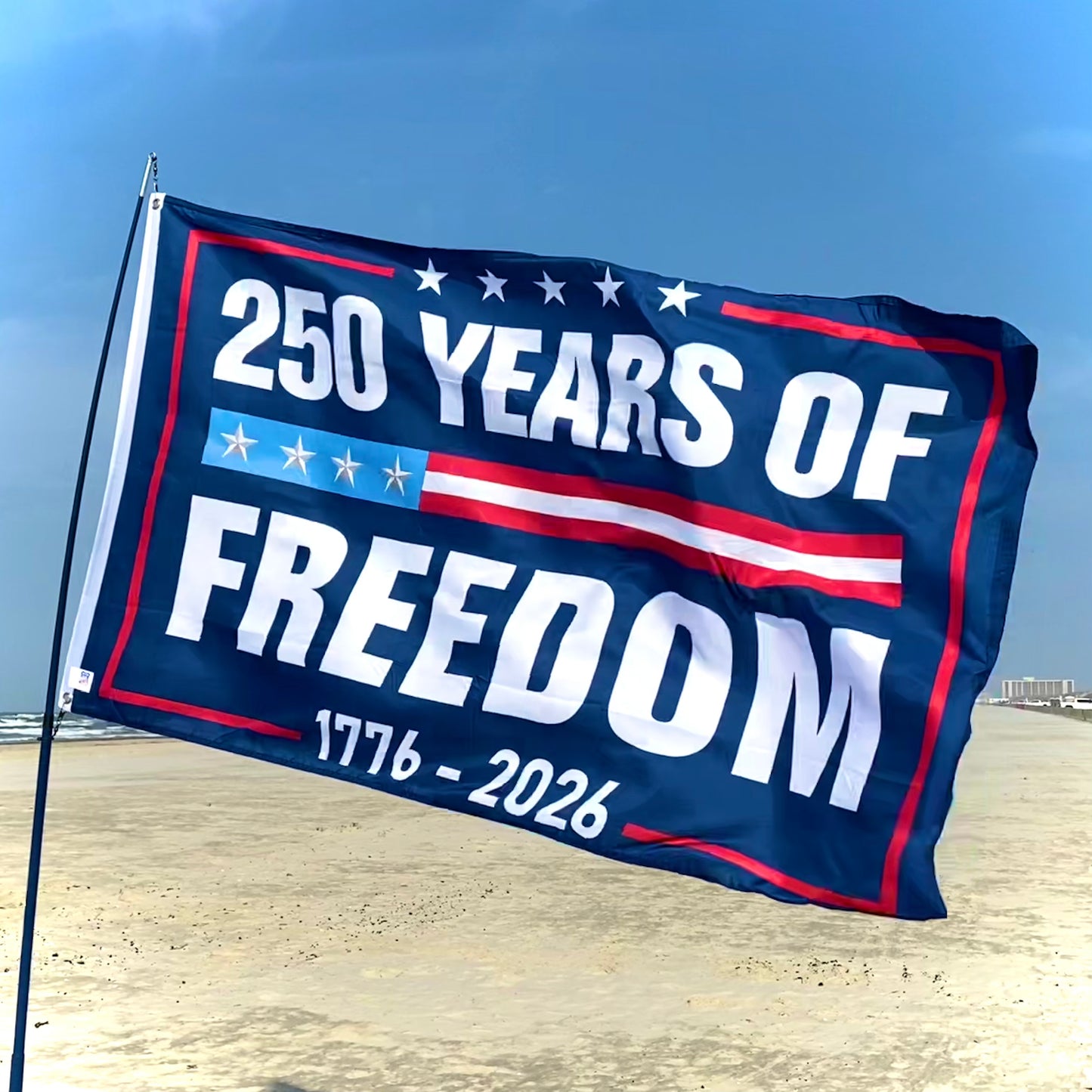 Flag with '250 Years of Freedom' text on a beach