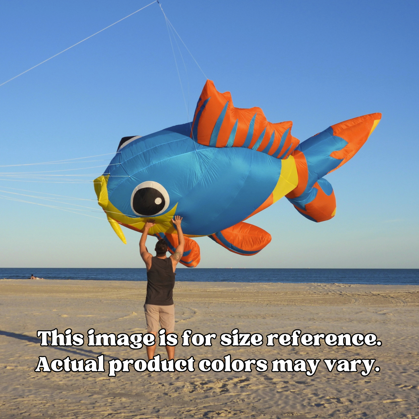 Person holding a large inflatable fish kite on a beach with ocean and sky in the background.