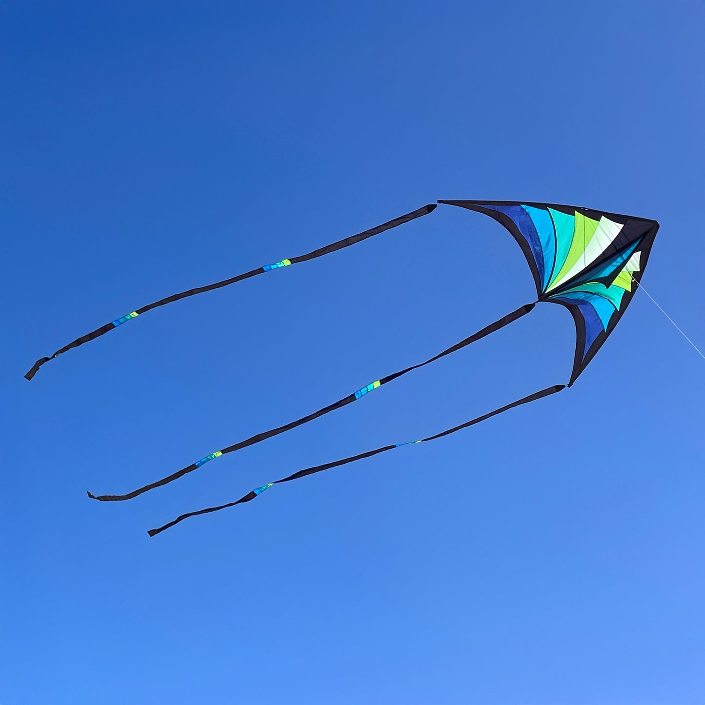 Colorful kite with long tails against a clear blue sky