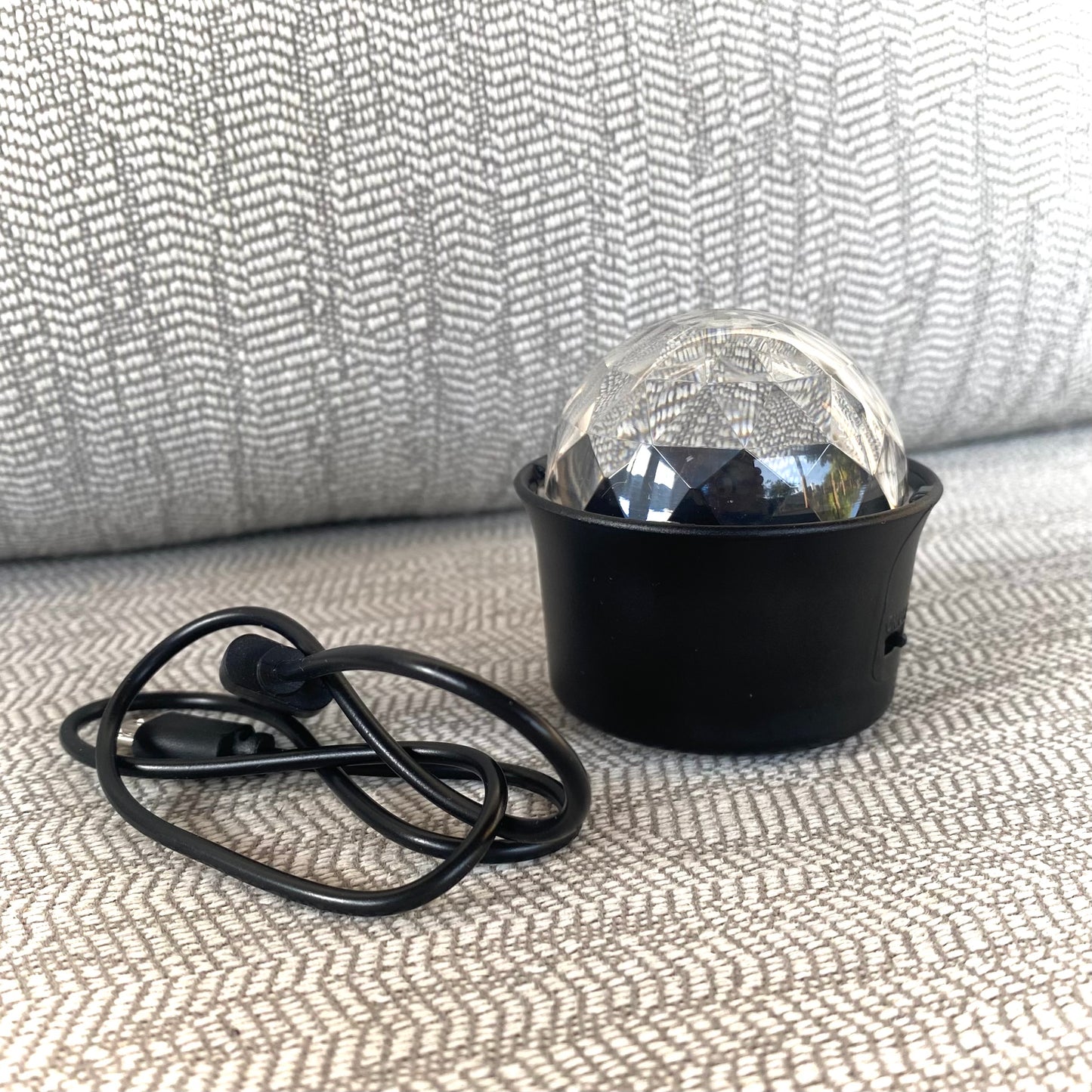 Black outdoor light fixture with clear glass cover on a textured surface