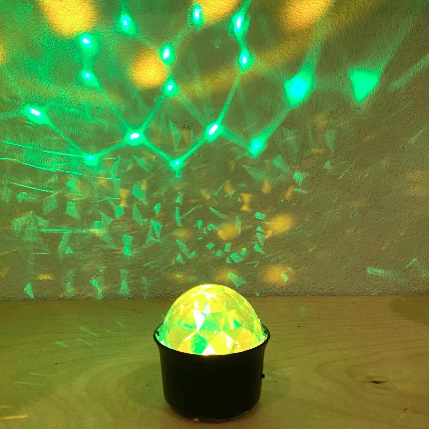 Disco ball projecting green and yellow lights on a wall