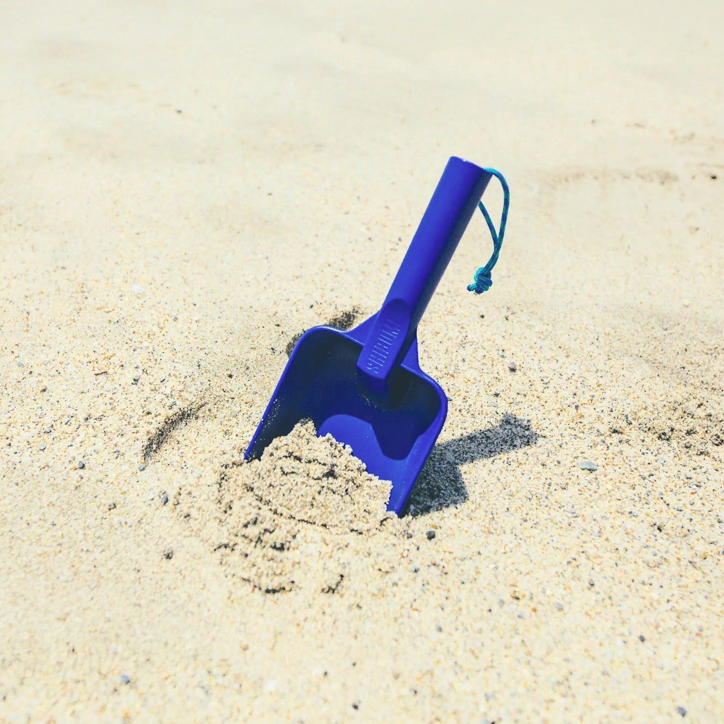 Blue sand shovel on a sandy surface