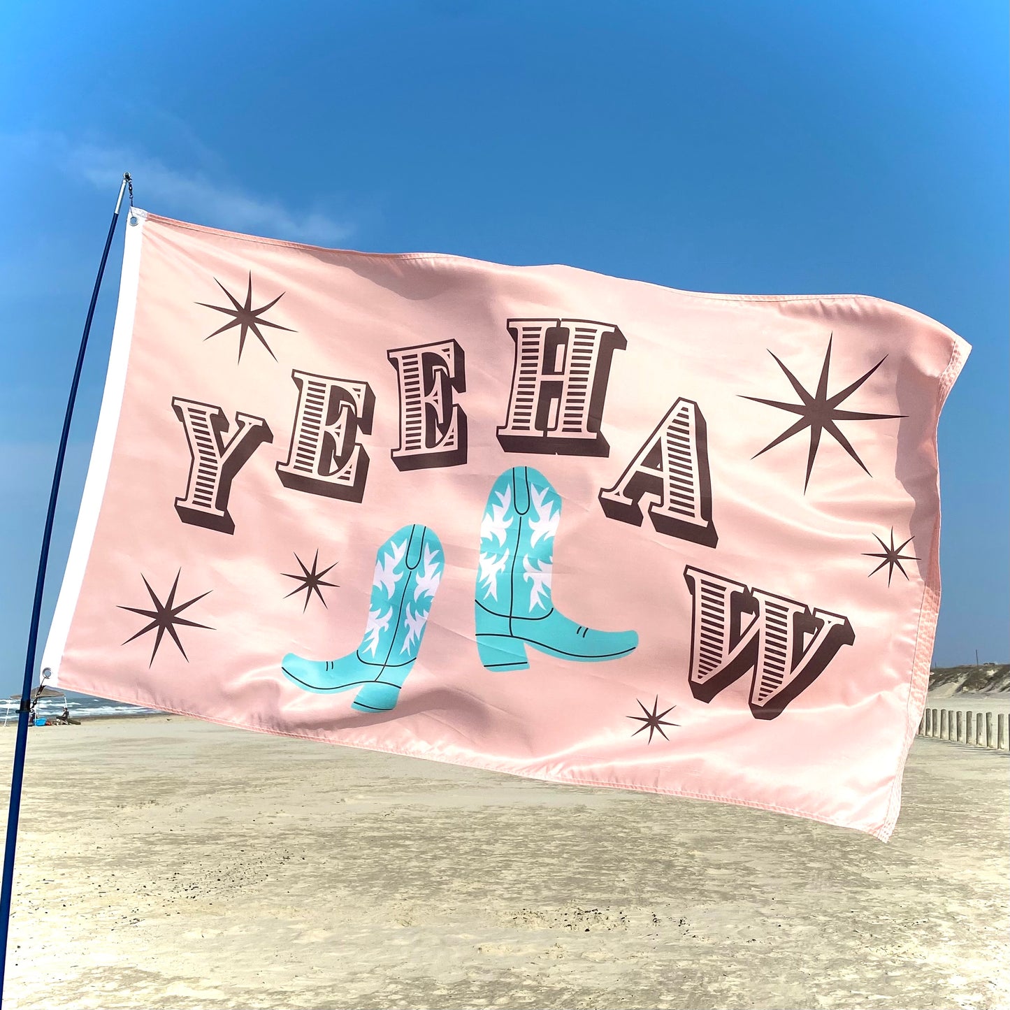 Pink flag with 'YEEHAW' and cowboy boots against a blue sky