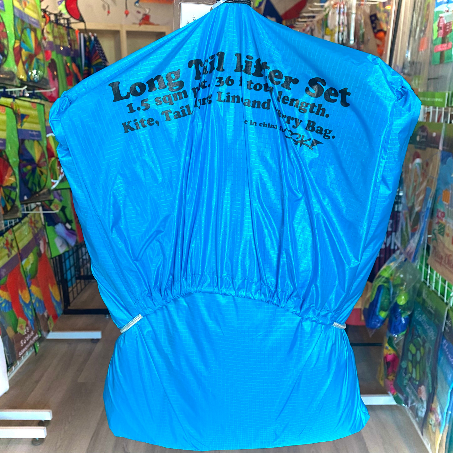 Blue kite bag with text in a store setting. 