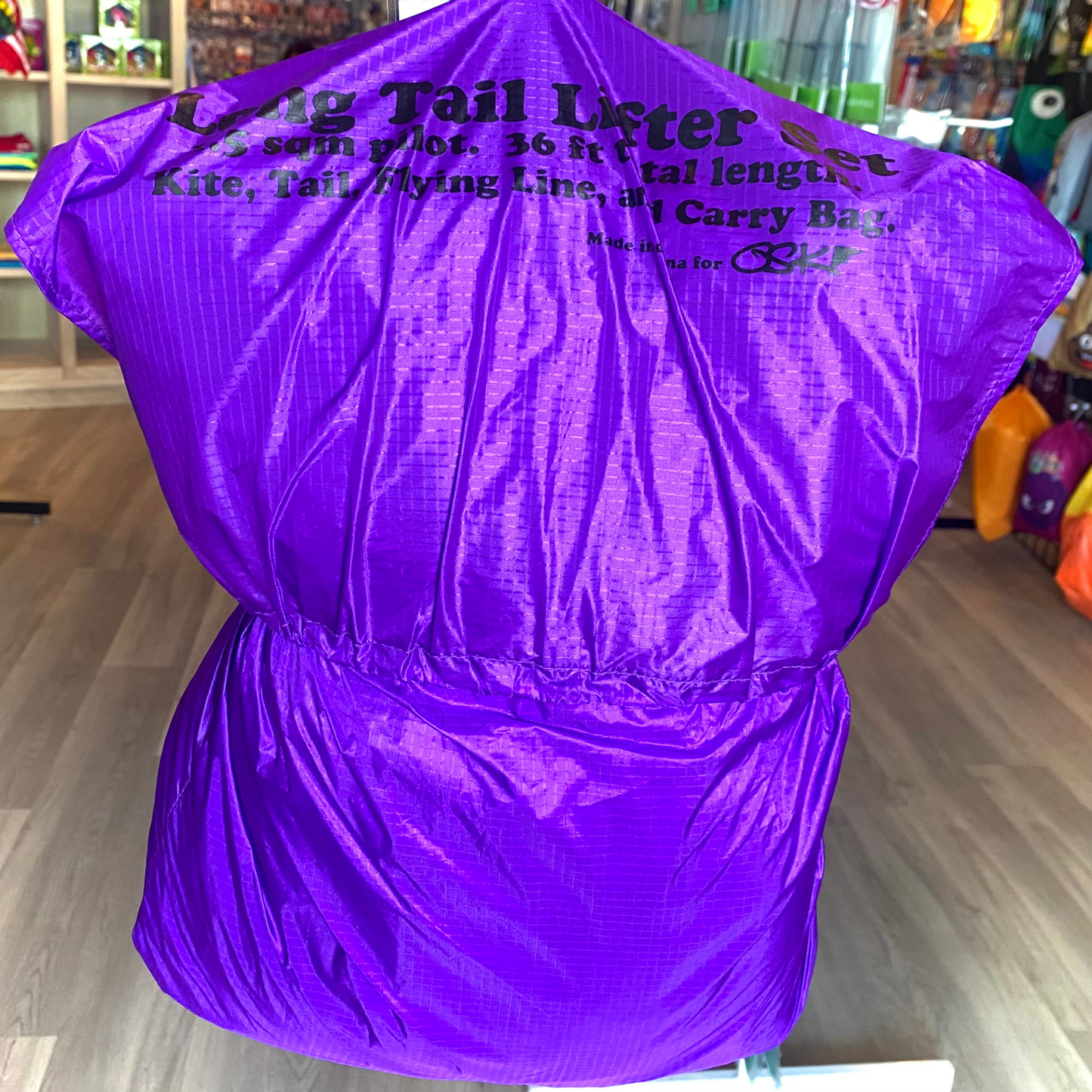 Purple kite carrying bag with text in a store setting
