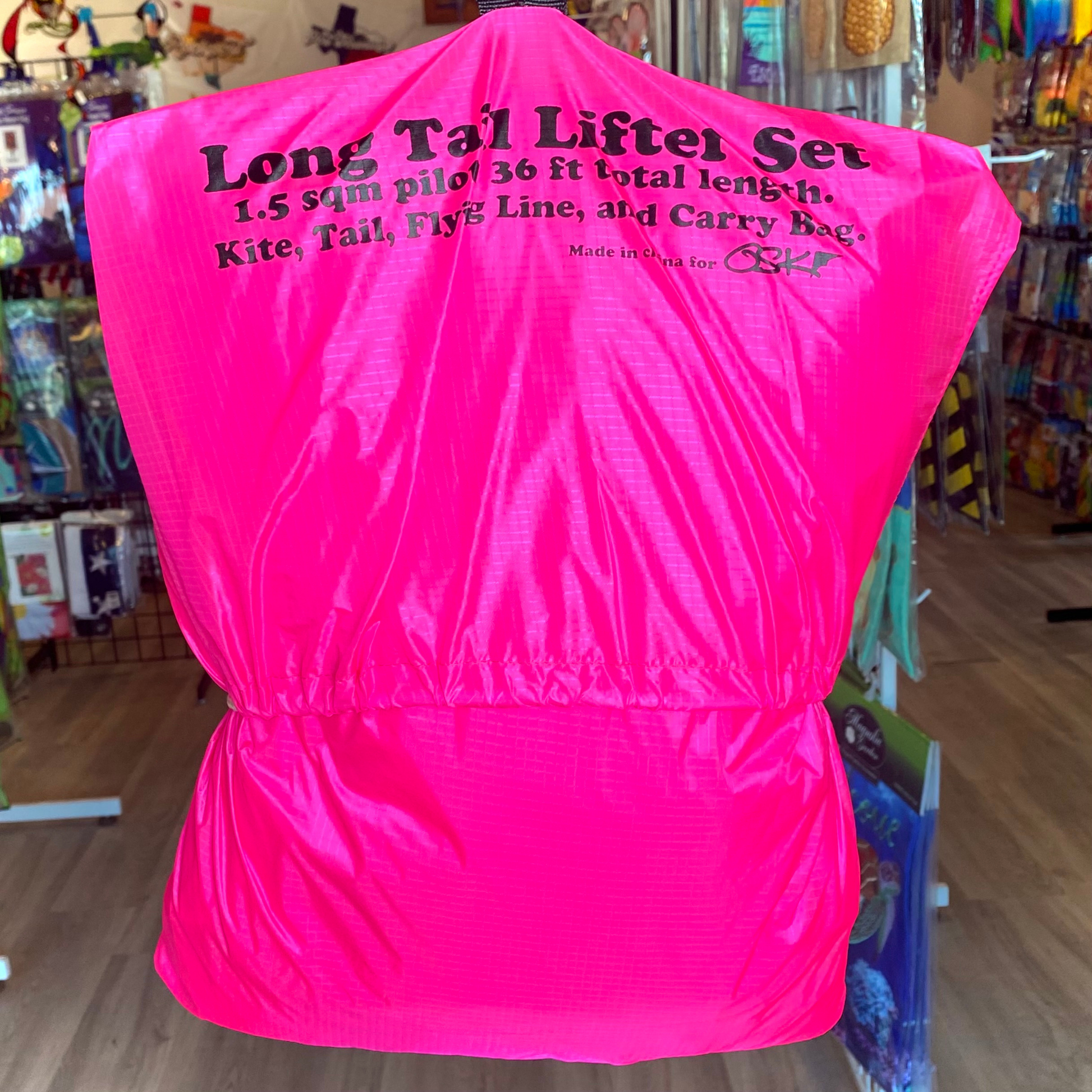 Pink kite bag with text on the back in a store setting