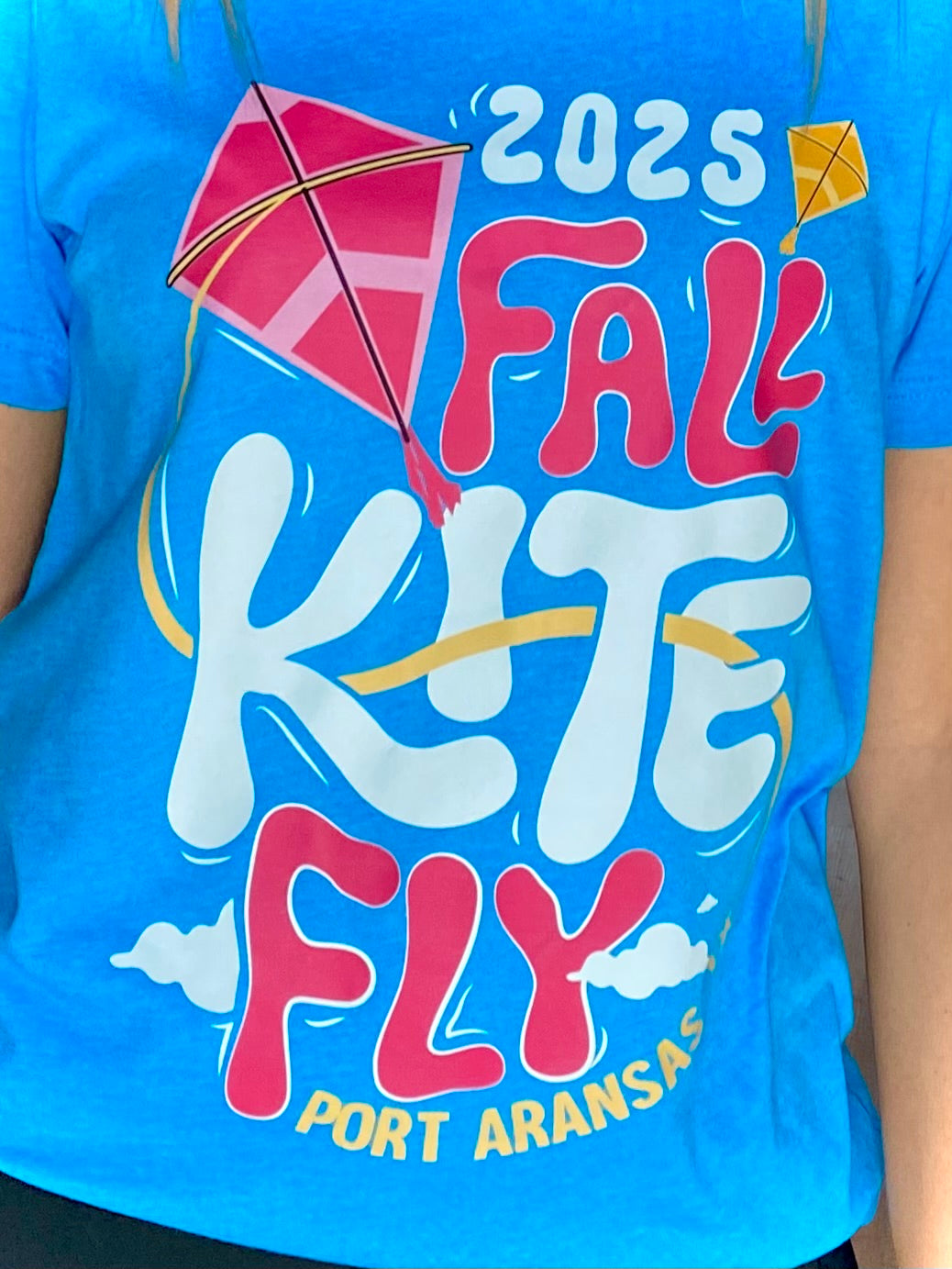 Blue t-shirt with '2025 Fall Kite Fly Port Aransas' text and kite graphics.