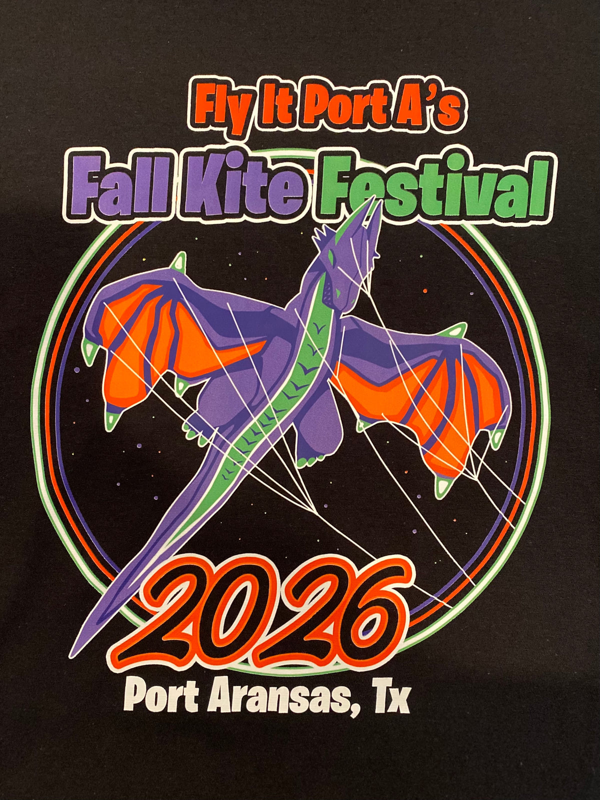 A black graphic print featuring a stylized purple and orange dragon kite with the text 'Fly It Port A's Fall Kite Festival 2026 Port Aransas, Tx' in colorful lettering.