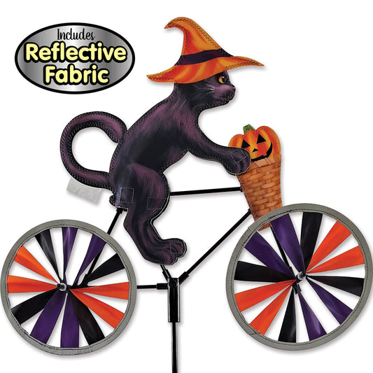 Halloween yard sign featuring a black cat riding a bicycle with orange, purple, and black striped wheels, wearing an orange witch hat, with a pumpkin basket on the handlebar. Includes reflective fabric.