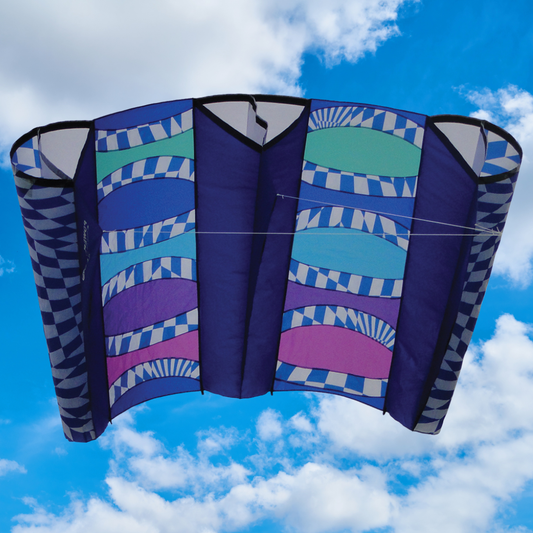 Colorful sled kite with geometric patterns against a blue sky with clouds