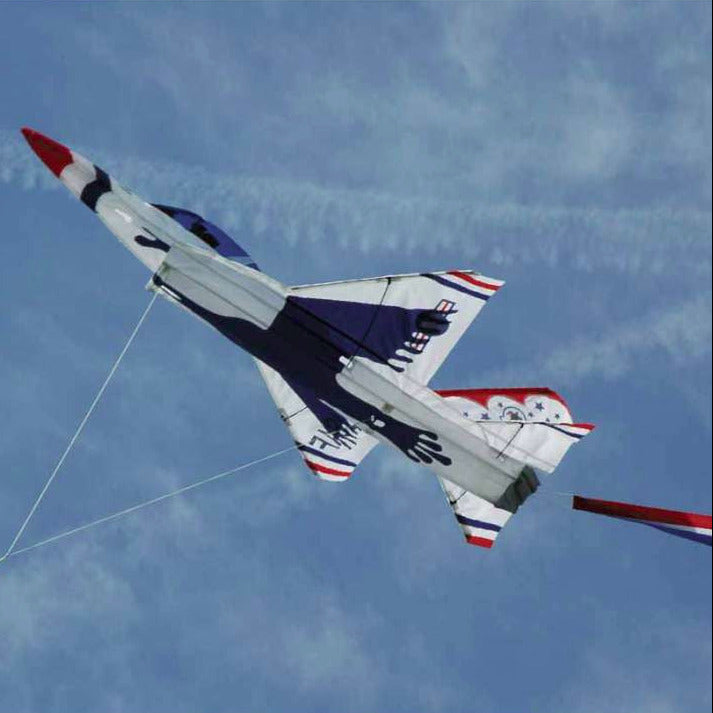 Airplane kite in the shape of a fighter jet with red, white, and blue colors against a blue sky.