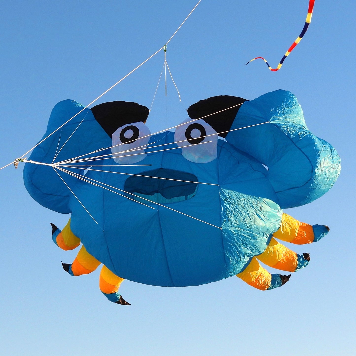 Blue kite shaped like a crab against a clear blue sky