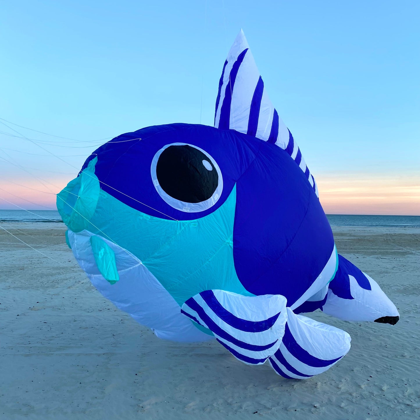 Inflatable fish-shaped kite on a beach with a clear sky