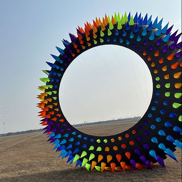 Colorful circular bol kite in a field with a clear sky.
