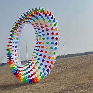 Colorful circular kite in a field with a clear sky.