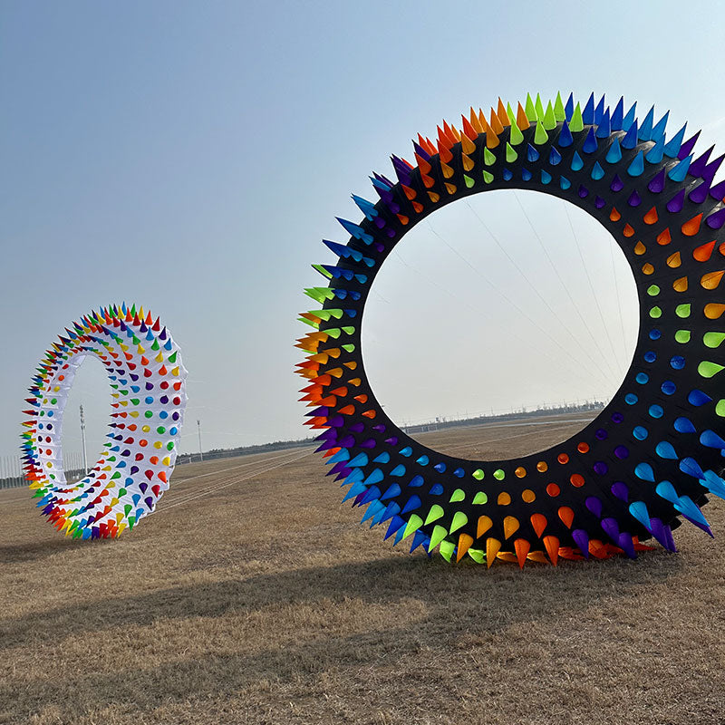 Colorful circular kite bol in a field with a clear sky.