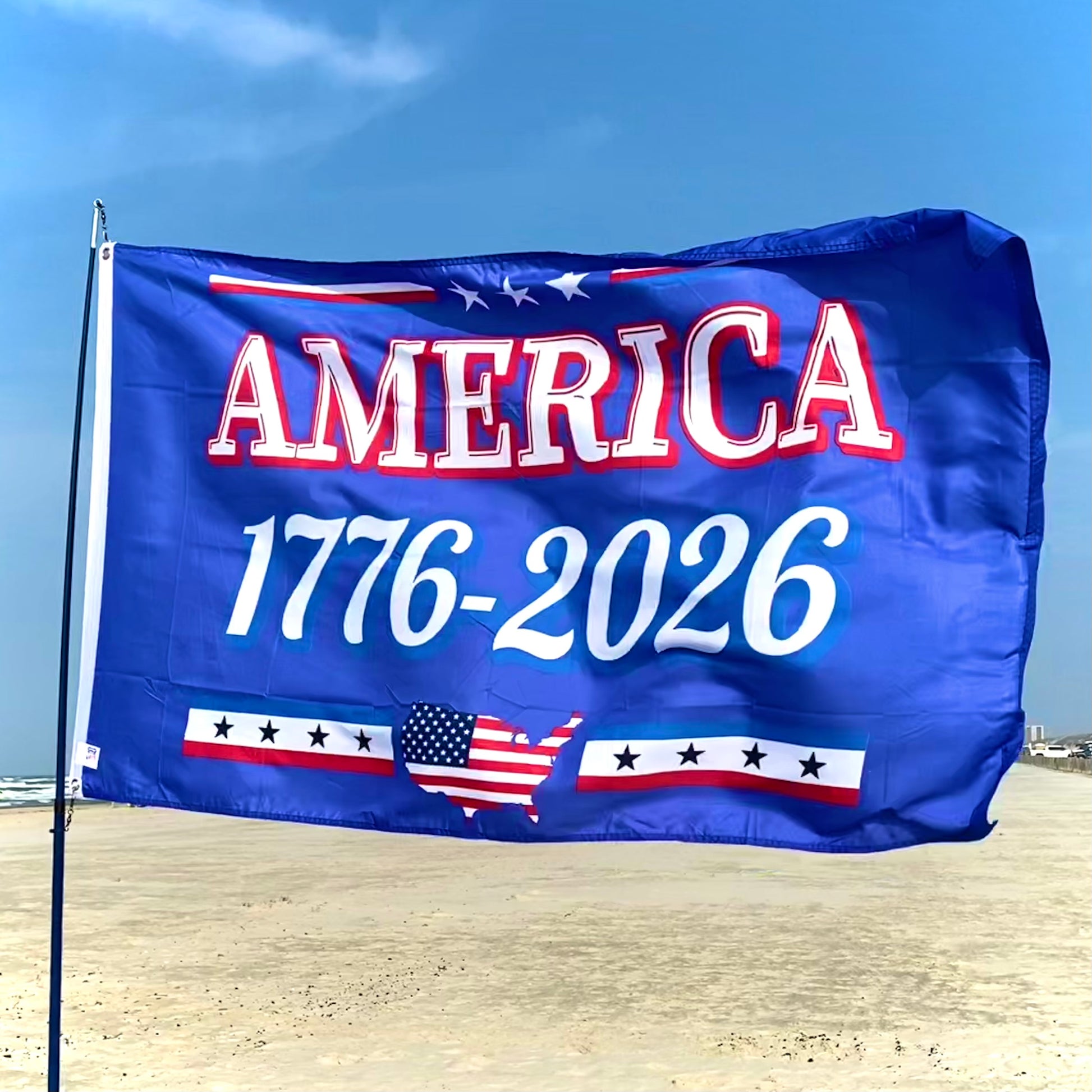 Flag with 'AMERICA 1776-2026' text on a beach