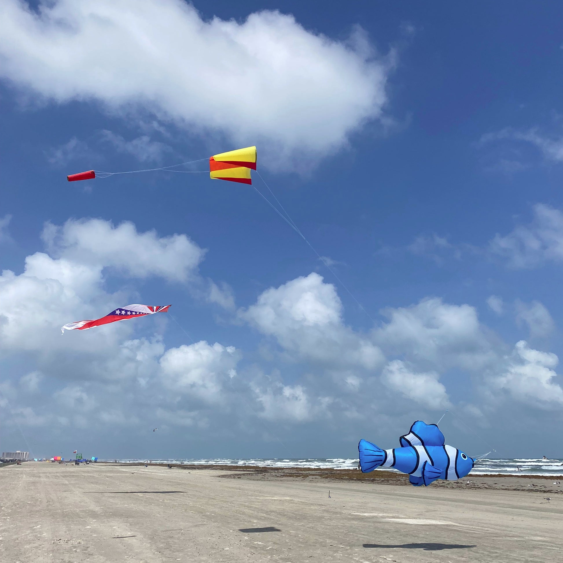 Kites flying in the sky with a beach and pier in the background