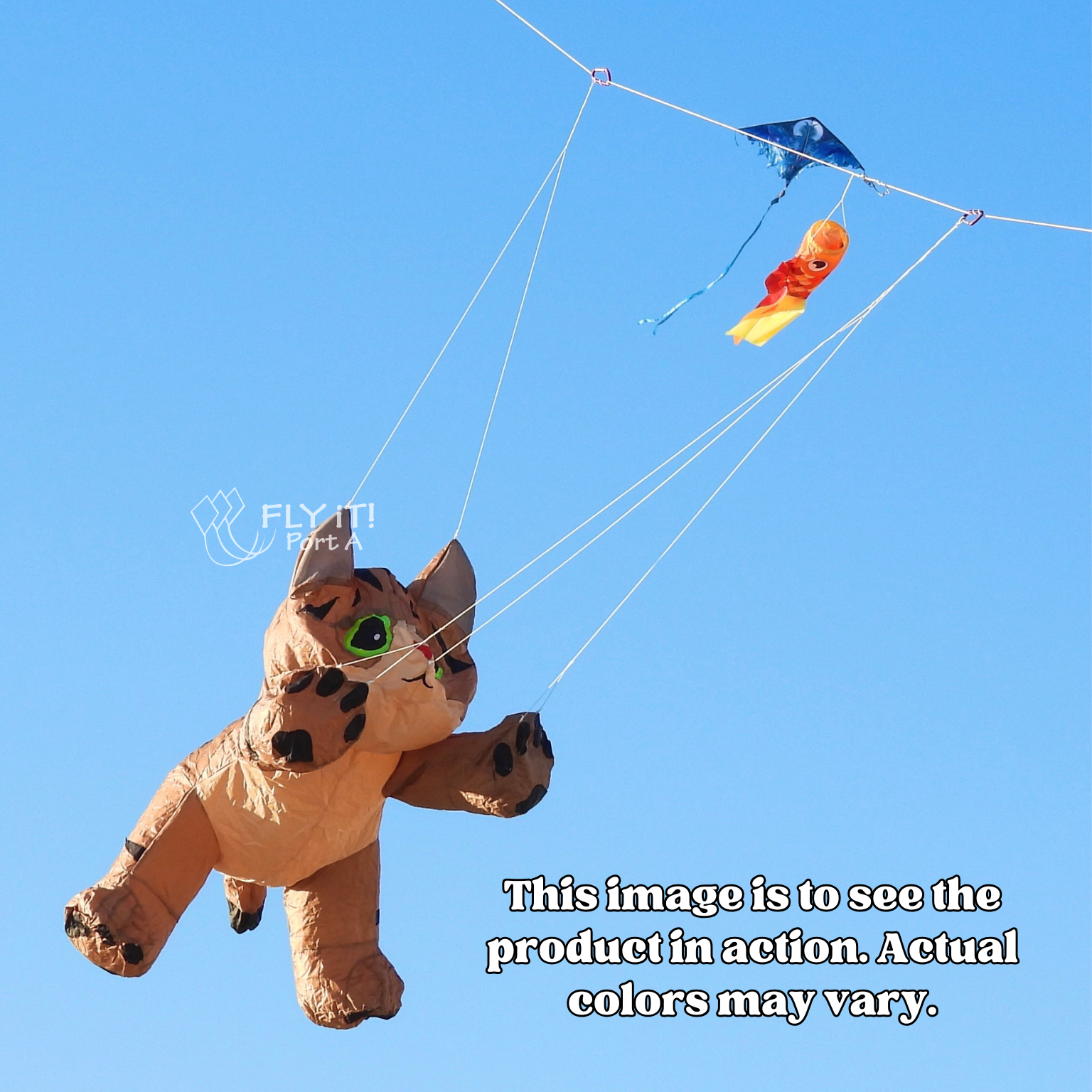 A large inflatable cat-shaped kite flying high in the sky, with thin strings connecting it to kite line. The background is a clear blue sky, and a watermark with text is visible in the center.