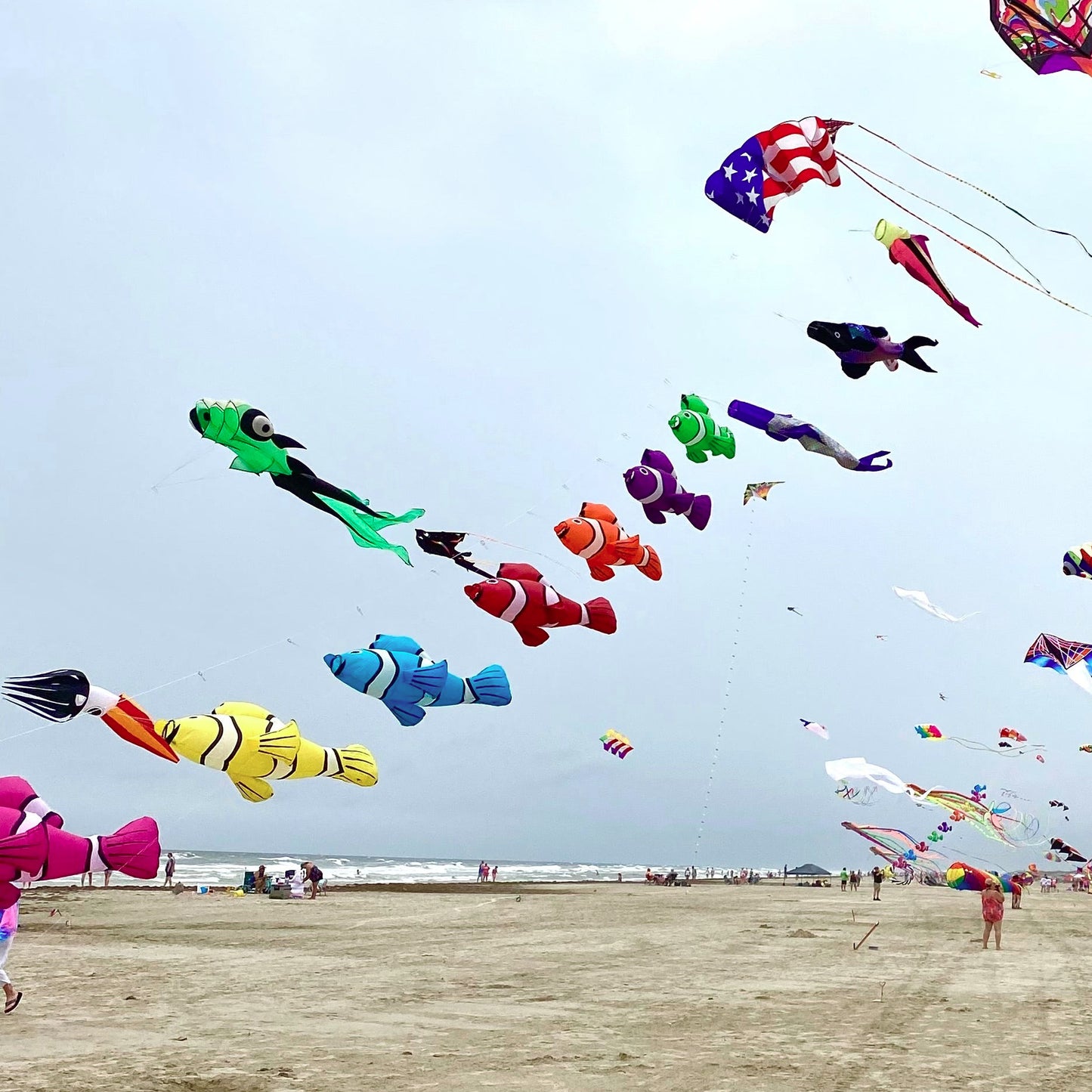 Colorful kites flying over a sandy beach with people below.