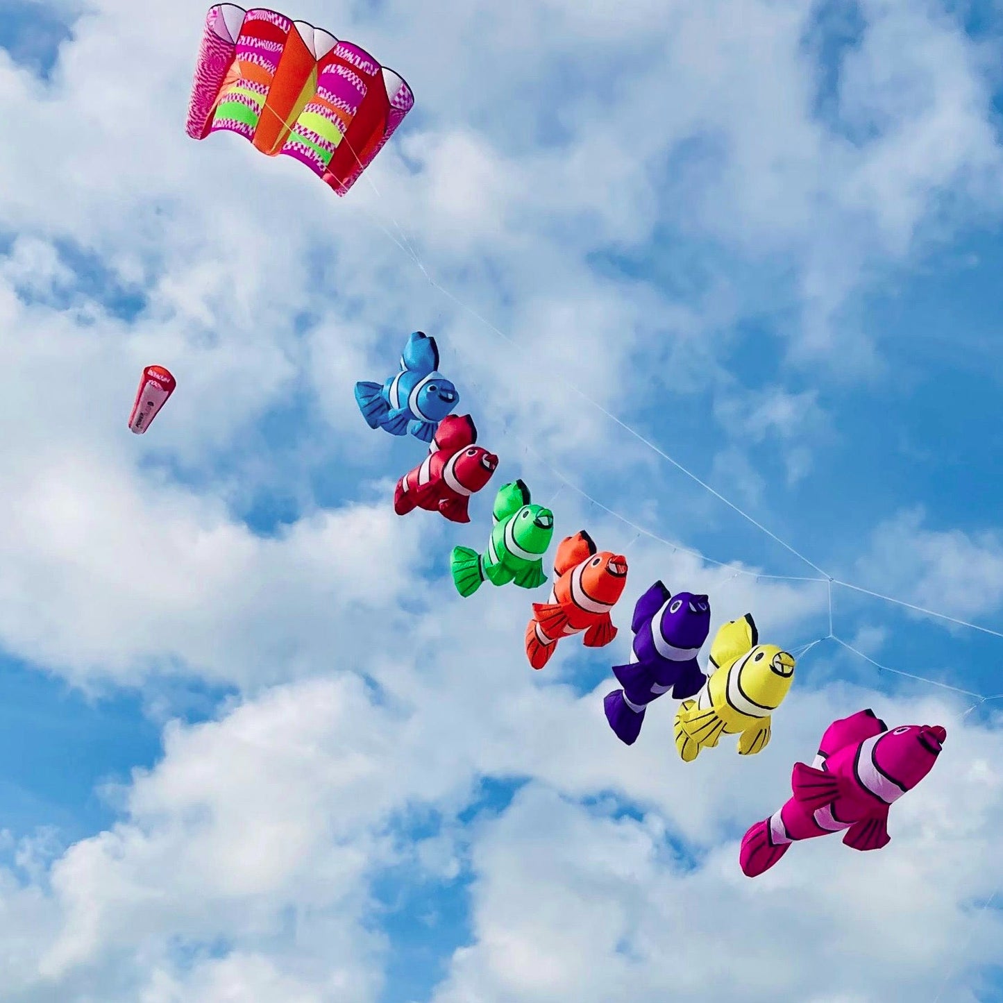 Colorful fish-shaped kites flying high in a blue sky