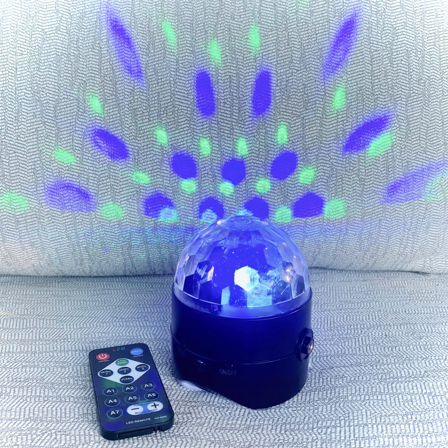 Colorful disco ball with remote control on a textured surface
