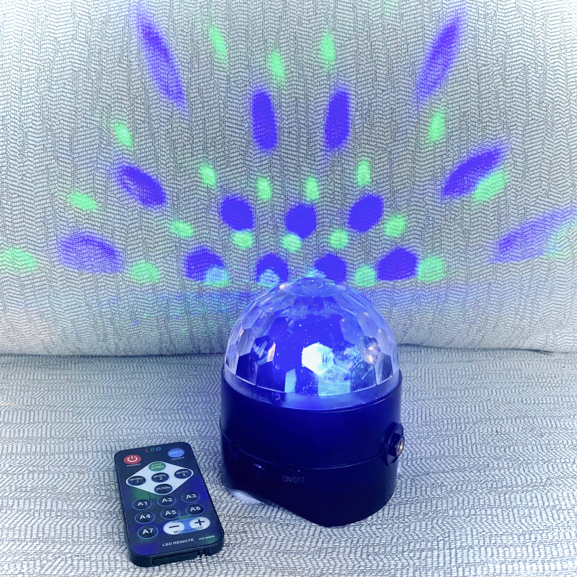 Colorful disco ball with remote control on a textured surface