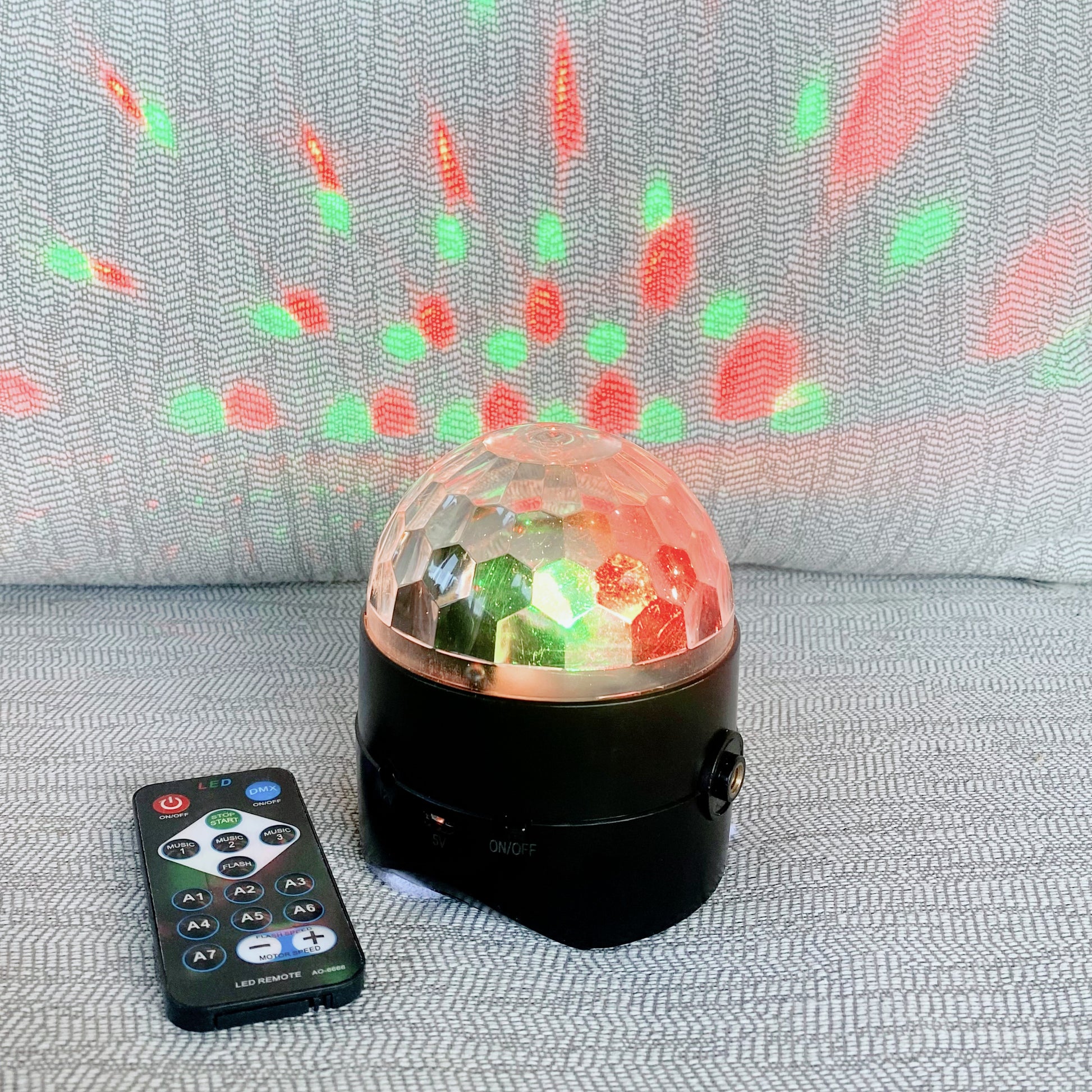 Colorful disco ball with remote control on a textured surface