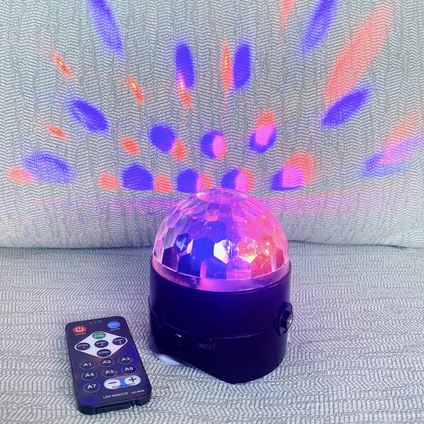 Colorful disco ball with remote control on a textured surface
