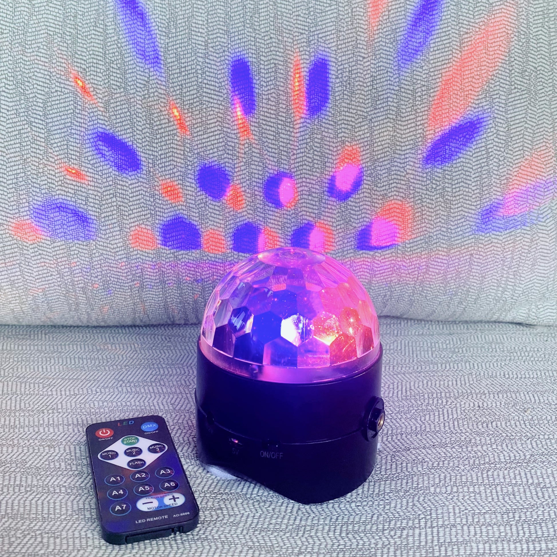 Colorful disco ball with remote control on a textured surface