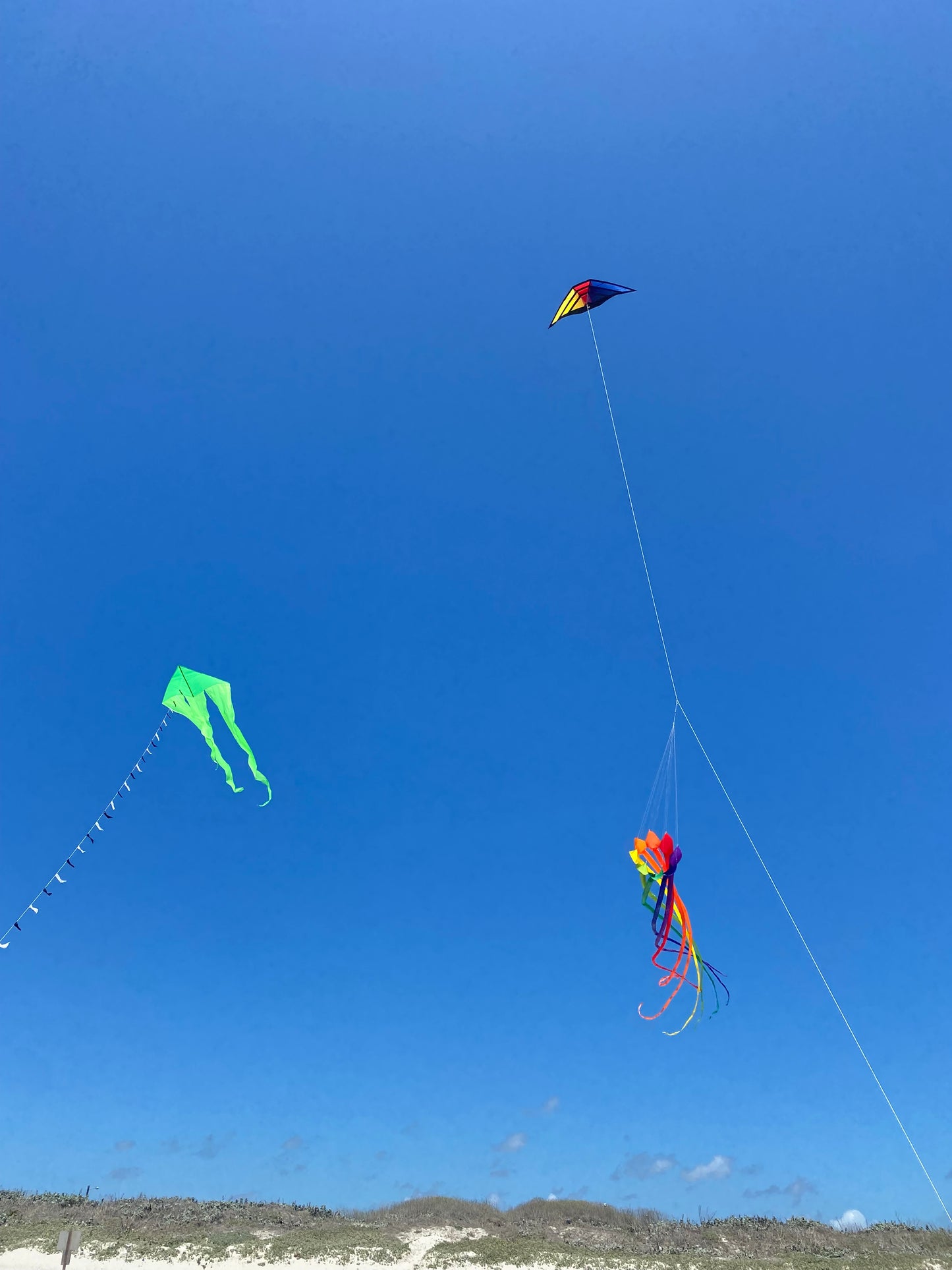 Three colorful kites flying against a clear blue sky.