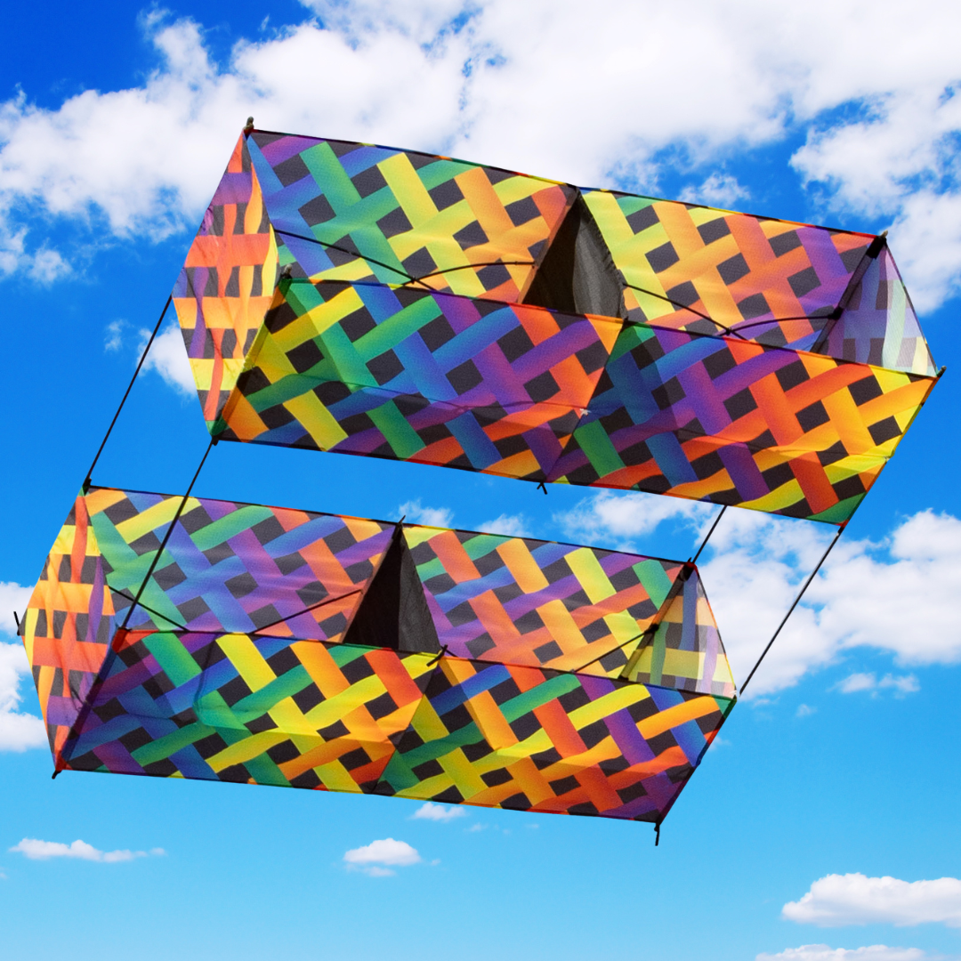 Colorful geometric-patterned box kite against a blue sky with white clouds