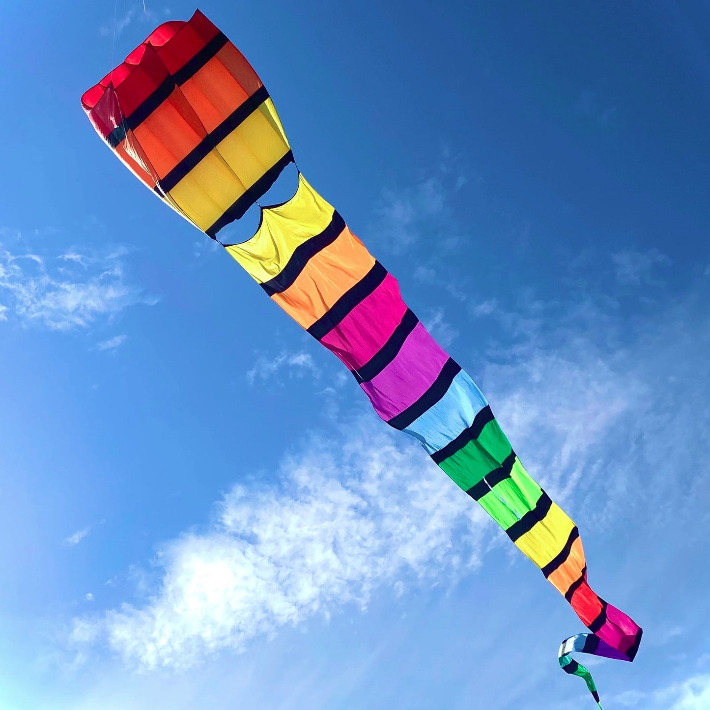 Colorful kite flying against a blue sky with some clouds.