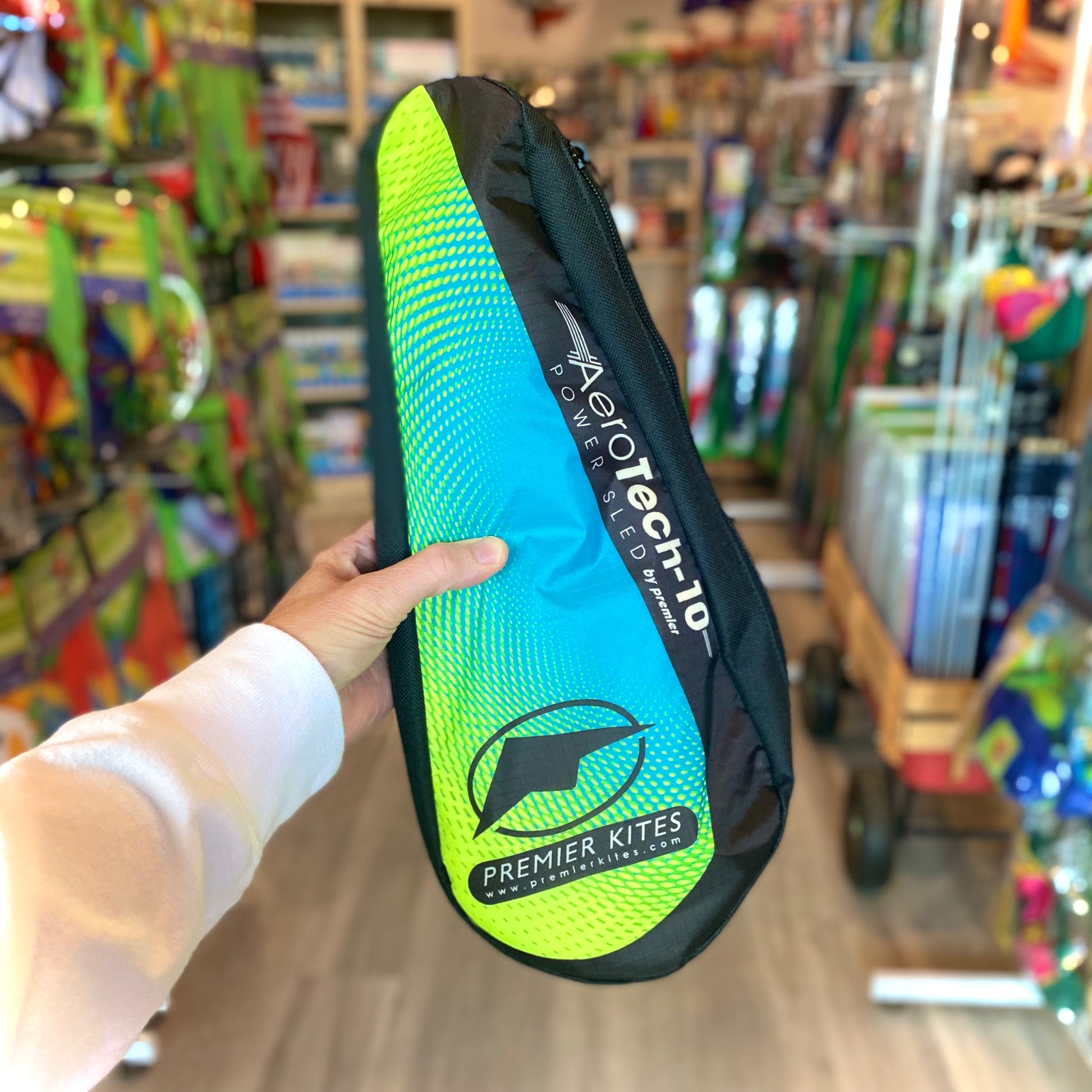 Hand holding a Premier Kites kite bag with 'AeroTech' branding in a store setting.