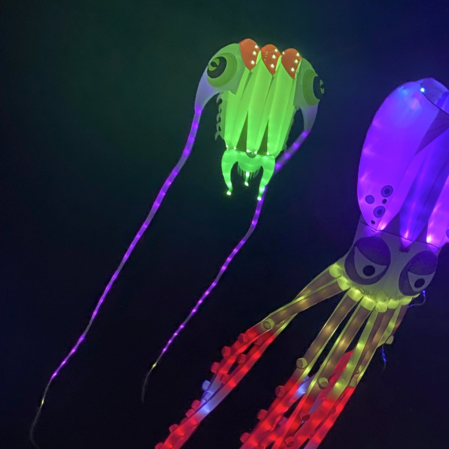 Colorful jellyfish-shaped kite with glowing lights against a dark background
