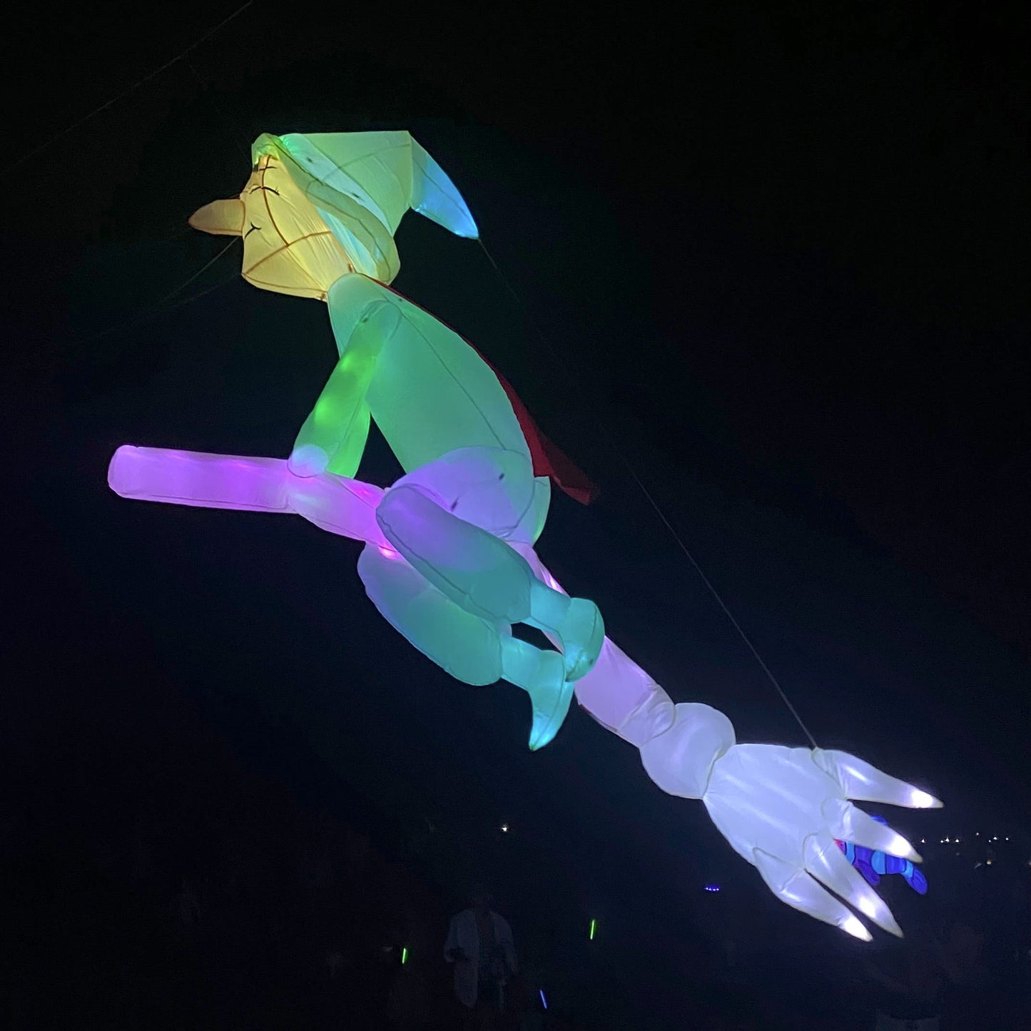 Colorful inflatable line laundry witch on a broom against a dark background