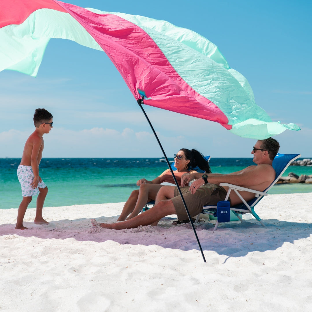 Family on a beach with a Mint and Berry Shibumi providing shade