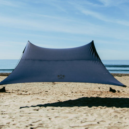 Navy NESO beach shade on a sandy beach with ocean in the background