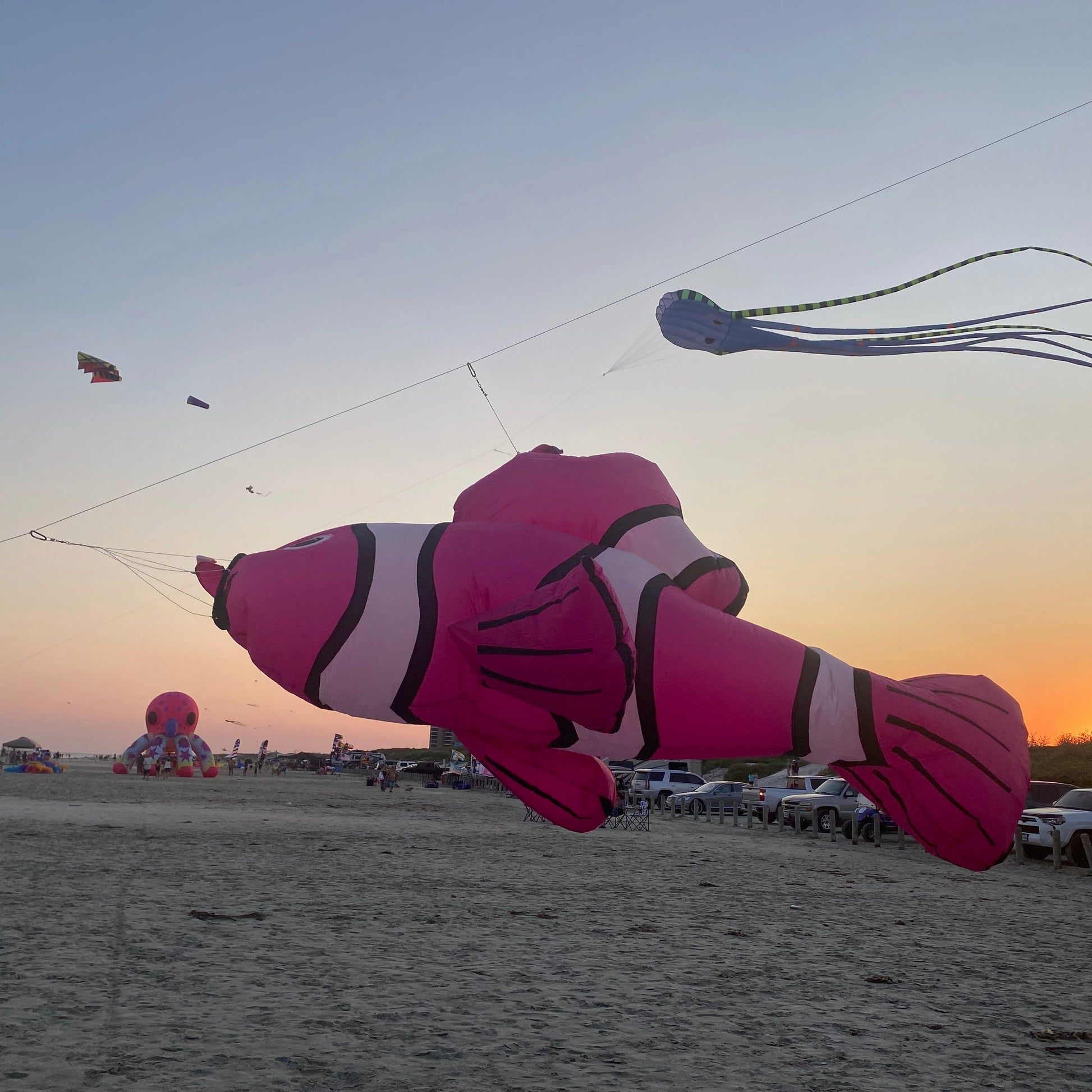 Inflatable clownfish kite flying over a beach at sunset