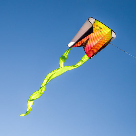 Colorful kite with a green tail against a clear blue sky