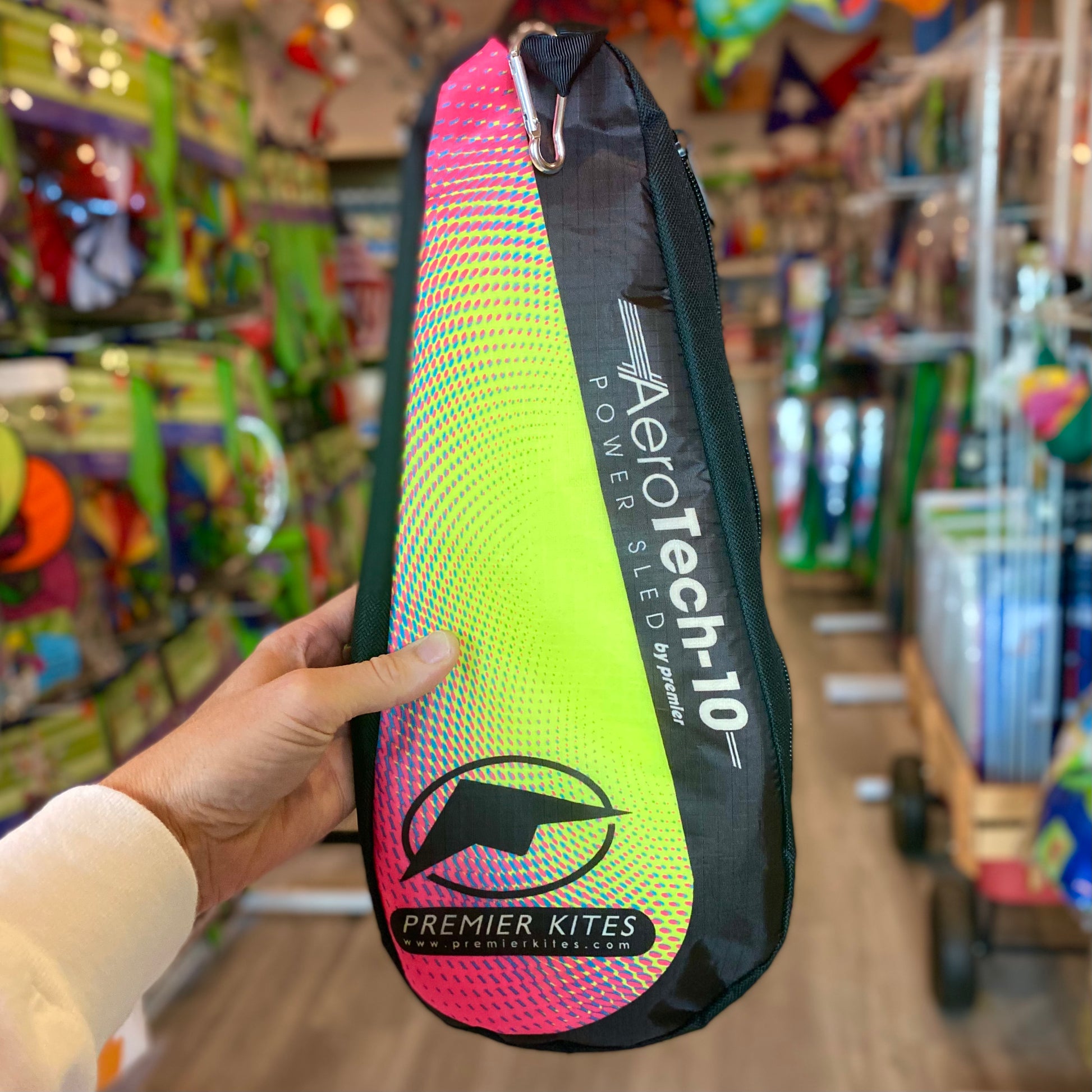 Aerotech-10 kite power sled bag held in a hand with a store interior background