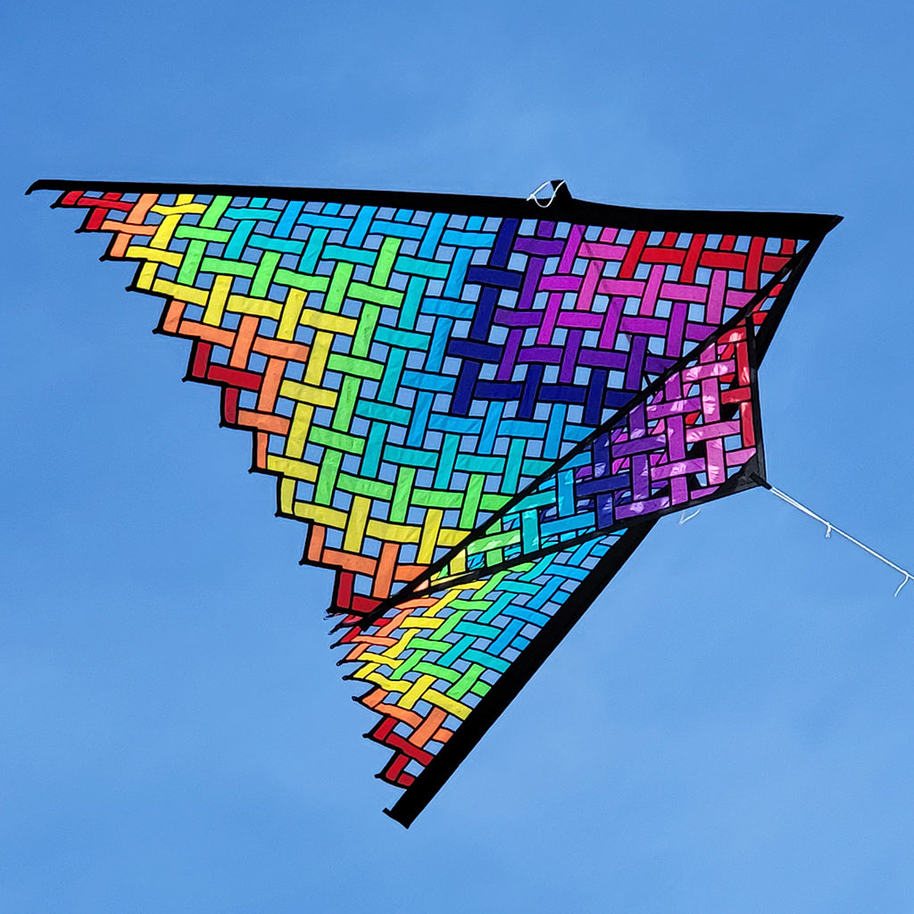 Colorful geometric-patterned kite against a clear blue sky