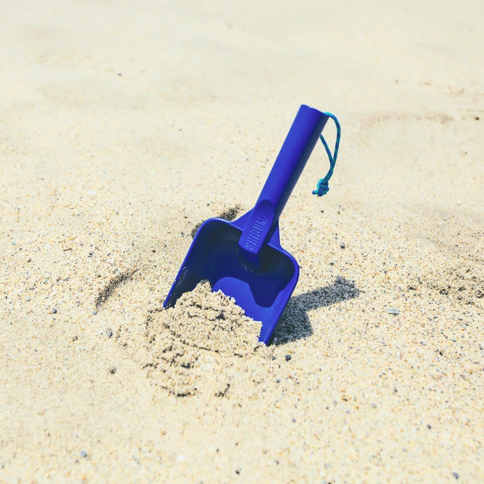 Blue sand shovel on a sandy surface