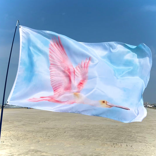 Flag with a pink spoonbill design waving on a beach