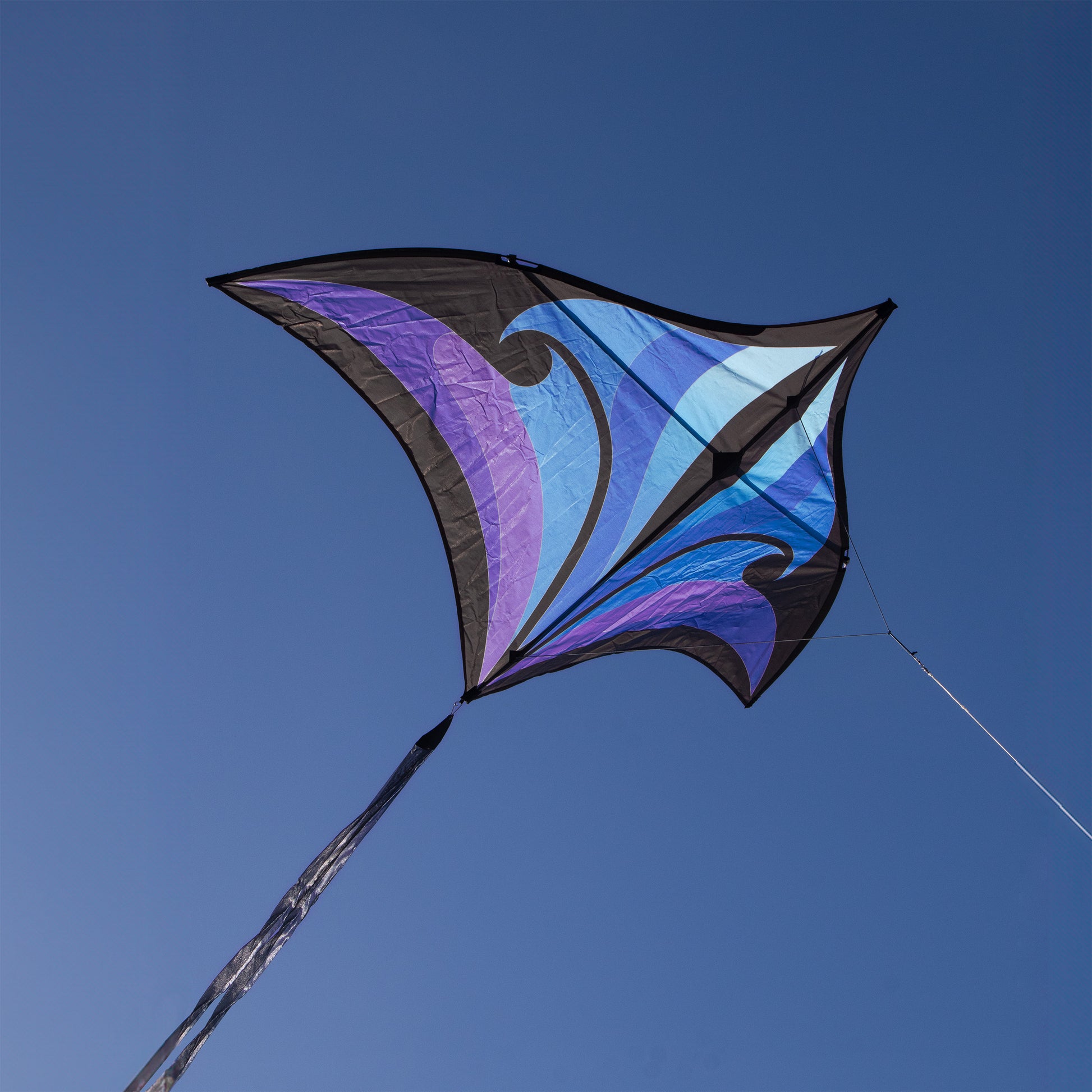 Colorful kite with a blue and purple design against a clear blue sky