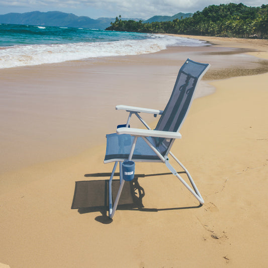 Beach chair on a sandy beach with ocean and mountains in the background
