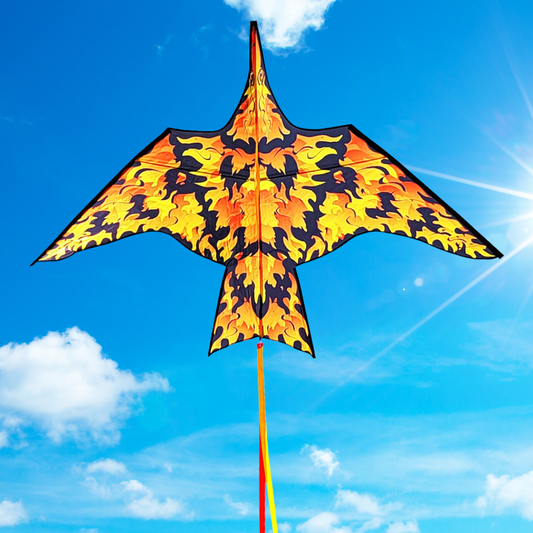 A colorful kite designed in a bird-like shape with a flame pattern in yellow and black, flying against a blue sky with few clouds.