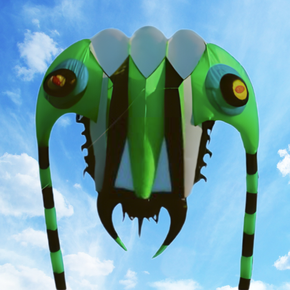Green and black kite shaped like a trilobite against a blue sky with white clouds