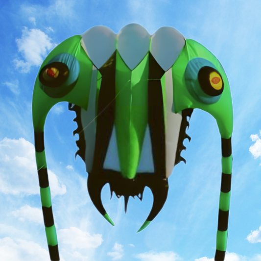 Green and black kite shaped like a trilobite against a blue sky with white clouds