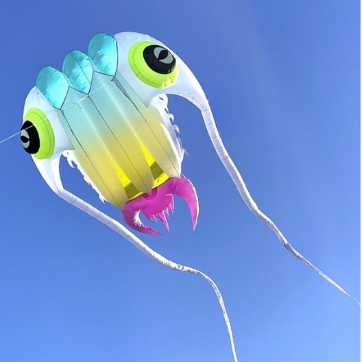 Colorful kite shaped like a trilobiteagainst a clear blue sky